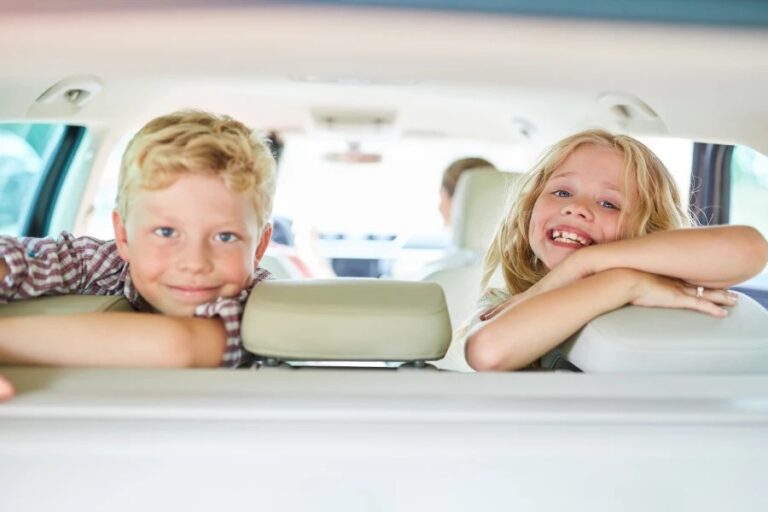 Two happy kids enjoying a car ride in the back seat, showcasing family travel comfort.